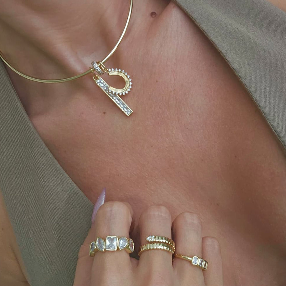 Gold horseshoe pendant necklace worn as a layering piece